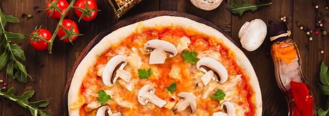 italian pizza with chicken and mushrooms on the wooden dark background (close top view).