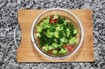 green broccoli salad in a glass plate on a wooden board background