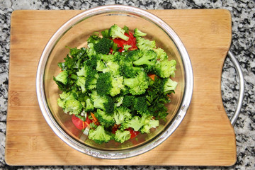 green broccoli salad in a glass plate on a wooden board background