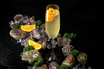 French 75 refreshing alcoholic beverage based on champagne, gin and sugar syrup on a black background with stones and ice. Cocktail card for a bar or restaurant.