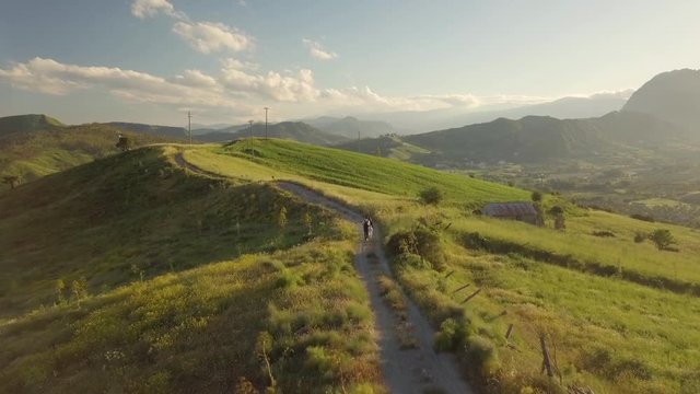 Ragazza balla su una strada sterrata in cima alla collina in campagna al tramonto.
