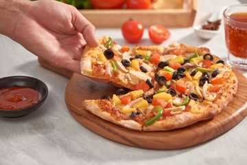 Hands holding fresh baked pizza with melting cheese.