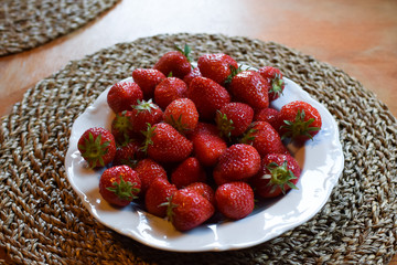 A plate of ripe and juicy strawberries.