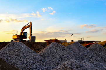 Heavy excavator bucket working in quarry on a background of sunset and blue sky. Mobile jaw stone...