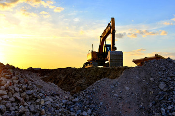 Heavy excavator bucket working in quarry on a background of sunset and blue sky. Mobile jaw stone...