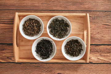 the white drinking bowls of assortment of dry tea in order on wooden background