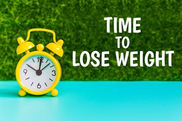 yellow alarm clock on the grass background with the inscription 