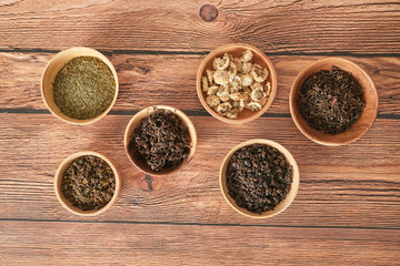 assortment of dry tea in white bowls on wooden surface
