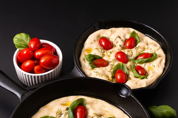 Food concept rising dough for vegan Homemade organic Focaccia in skillet iron pan on black background with copy space