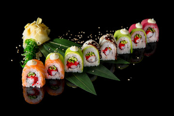 Sushi roll (Rainbow) with tuna, salmon, smoked coal, avocado, shrimp, egg omelette, cucumber and avocado on black background. Sushi menu. Japanese food.