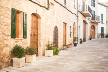 Fototapeta na wymiar a small cosy street on Mallorca, Spain; green plants in pots standing outside along walls