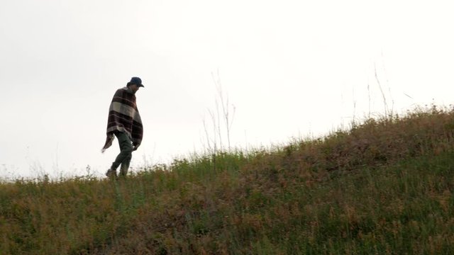 Lonely cowboy with poncho walks on the hill