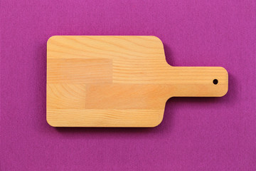 Kitchenware, top view vintage cutting wood board on purple tablecloth background