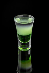 Green mexican. Alcoholic cocktails in shot glasses (shooters).  Cool drink from strong vodka, whiskey and sweet liqueurs isolated on black background. Cocktail card for a bar or restaurant.