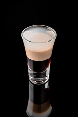 Alcoholic cocktails B-52 in shot glasses (shooters).  Cool drink from strong vodka, whiskey, coffee liqueur, baileys. Isolated on black background. Cocktail card for a bar or restaurant.