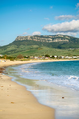 a tranquil beach scene with waves breaking and a mountain peak in Bolonia, Spain 