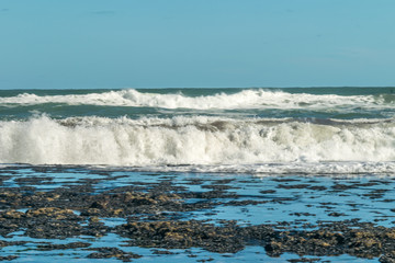 Sea waves hitting on the stones near the coast. White foam comes out of the waves white foam of a...