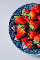 Fresh ripe strawberries in a blue and white plate