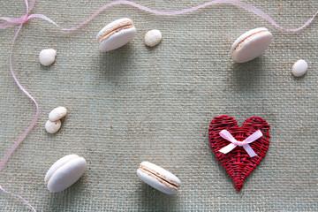 Fototapeta na wymiar Mother's day background with red heart and pink macarons.
