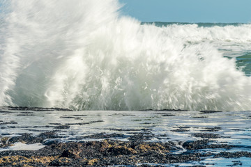 Sea waves hitting on the stones near the coast. White foam comes out of the waves white foam of a sea wave