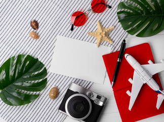 Flat lay travel concept: planner, passport, smartphone, camera, pen, star fish and monstera leaves on wooden background