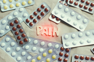 Pain word on craft paper background. Set of many pills plastic blisters. First aid kit. Pain killer. 