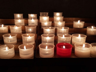 Red candle around white candles on black background. Business concept