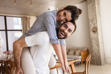 Photo of cute brunette couple in love smiling while hugging together in apartment