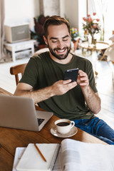 Photo of successful mature man using laptop and smartphone while working in flat