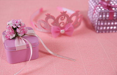 pink gift box with red ribbon and bow, flower and crown isolated on pink background.