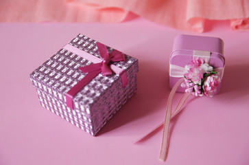 gift box with red ribbon and bow and flower isolated on pink background.