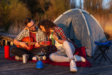 Obraz na płótnie Canvas Couple playing the guitar at a campsite