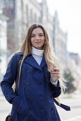 Pretty young woman posing on city street. Girl walking and enjoying spring day