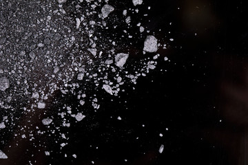 Crushed black eyeshadow for make up, close up on a dark background. Abstract dark and shine texture