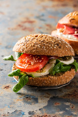 Italian Caprese sandwiches with fresh tomatoes, mozzarella cheese and lamb's lettuce, multigrain bun. Healthy food concept with copy space