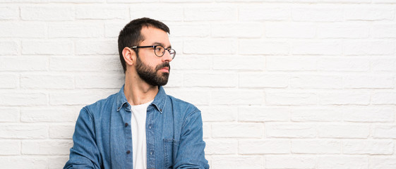 Handsome man with beard over white brick wall portrait