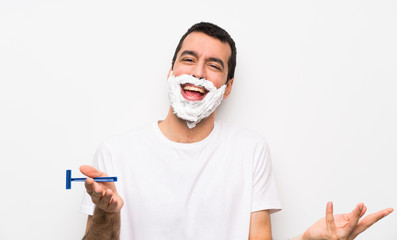 Man shaving his beard over isolated white background smiling
