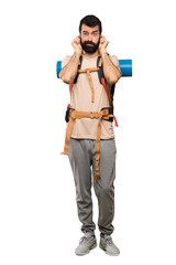 Hiker man frustrated and covering ears over isolated white background
