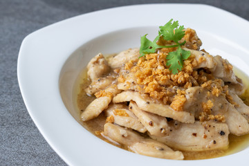 Fried chicken with garlic and black pepper in white dish on the concrete table.
