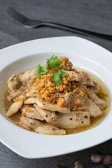 Fried chicken with garlic and black pepper in white dish on the concrete table.