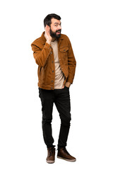 Fototapeta premium Handsome man with beard listening to something by putting hand on the ear over isolated white background