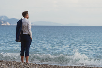 Businessman standing barefoot on the beach