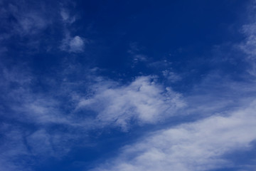 A deep blue sky with light white clouds background