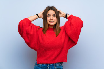 Young woman over isolated blue wall frustrated and takes hands on head