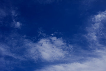A deep blue sky with light white clouds background
