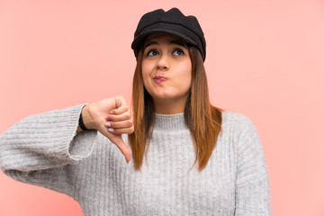 Fashion woman with hat over pink wall showing thumb down sign