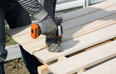 Man twists the screw into the board with a screwdriver