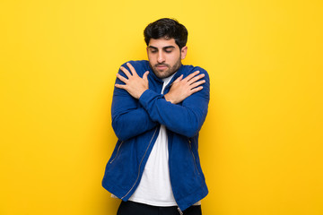 Man with blue jacket over yellow wall freezing