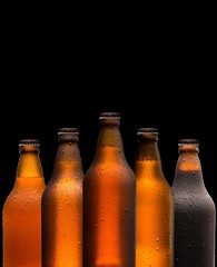 Branding and marketing concept for beer with a line of unopened unlabelled full blank brown bottles on a dark shadowy background conceptual of Oktoberfest or nightlife