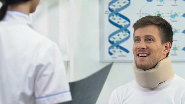 Happy man in foam cervical collar on doctors appointment, positive x-ray result